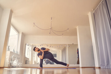 Male yoga practitioner doing prayer twist pose