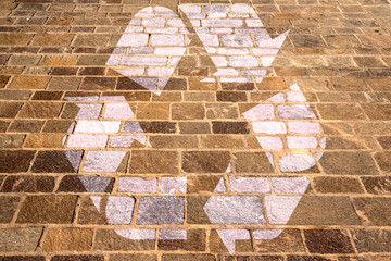 Recycle symbol drawn on the tiles of a pavement