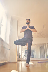 Bearded young man doing yoga exercise in studio