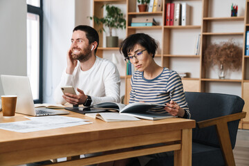 Fototapeta premium Photo of young colleges talking on cellphone and examining documents