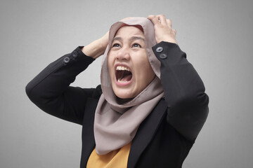 Portrait of Asian muslim lady wearing hijab shows angry screaming gesture, stress depressed...
