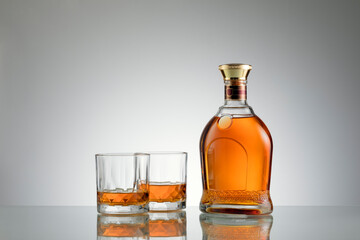 close up view of bottle of whiskey and a glasses aside on grey back. 