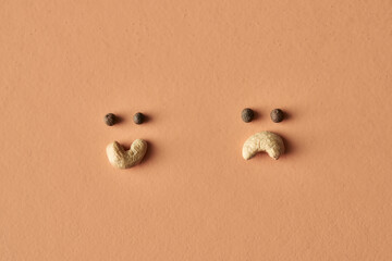 Fototapeta na wymiar Happy and sad smiley face made of cashew and pepper isolated on beige background, conceptual photo for food blog or ad