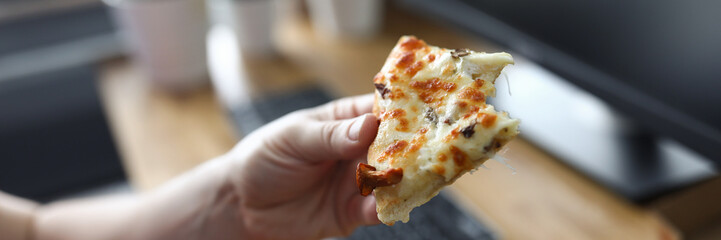 Man eating pizza at workplace close up
