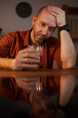 Frustrated mature man has life problems he sitting at the table and thinking about this and drinking alcohol