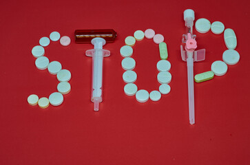 Medication white, colorful round tablets in word Stop isolated on red background. Pills ampoule syringe with needle. Concept of health, treatment, choice healthy lifestyle. For advertising