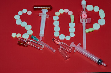 Medication white, colorful round tablets in word Stop isolated on red background. Pills ampoule syringe with needle. Concept of health, treatment, choice healthy lifestyle. For advertising