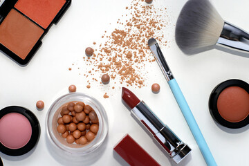 Bright makeup: pink lipstick, blush in balls, eye shadow and cosmetic brushes on a white background. Makeup products.
