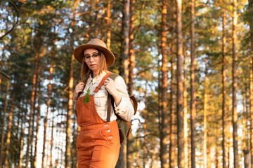 Portrait of woman botanist with backpack on ecological hiking trail in summer. Naturalist exploring wildlife and ecotourism adventure walking in a wildlife national park