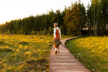Woman botanist with backpack on ecological hiking trail in summer outdoors. Naturalist exploring...