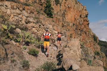 Group of young adults training and running together through trails on the hillside outdoors in nature.