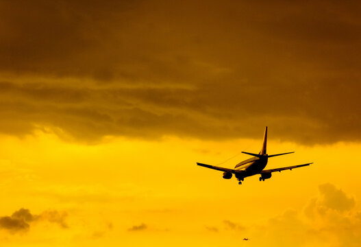 The plane comes in to land on the background of clouds at sunset