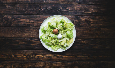 plate of lettuce with two eggs on a wooden board