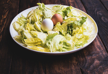 plate of lettuce with two eggs on a wooden board