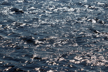Glittering water surface texture of deep blue sea. Soft waves, ripple water for background