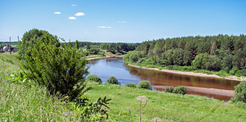 Fototapeta premium A clear river runs between green banks.