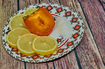 Lemon and persimmon on old wooden background. Shallow depth of field, toned photo.