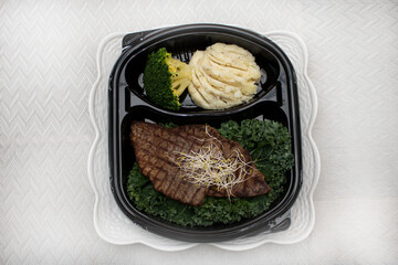 Steak in a black plate with mashed potato and broccoli