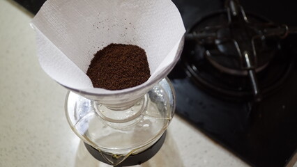 Drip coffee, pouring water over roasted.Man pouring water from the kettle into the coffee filter. Fresh morning pour over coffee blossoms in the dripper.
