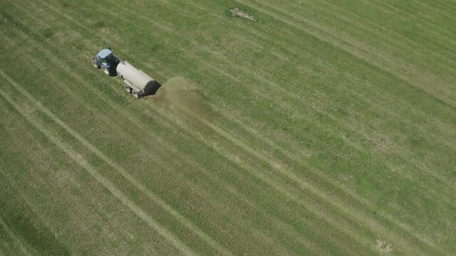 Aerial view of farming tractor. Natural eko fertilizer with manure.  Trailer fertilizes a freshly plowed agriculural.