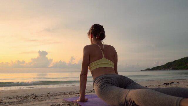 Woman practicing yoga and doing stretching at sunrise