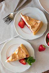 Slice of delicious strawberry tart with meringue on wooden background. Summer food. Top view
