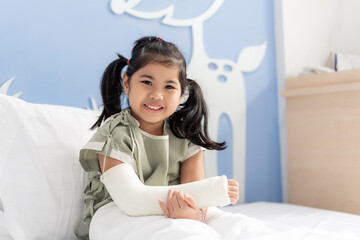 Asian girl treatment in hospital lying on the bed hurting with broken arm back from surgery.