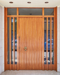 Contemporary apartment building entrance natural wood door by the sidewalk, Athens Greece