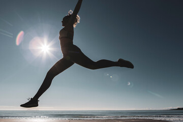 Young female dancer dances at sunset wearing sportswear . Silhouette backlight of the sun with body movements. Freedom and happiness concept.