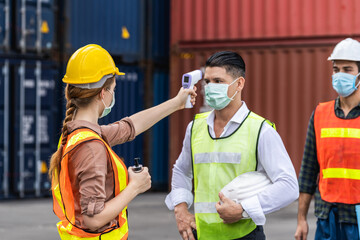 Engineer worker waring surgical mask checking body temperature using infrared digital thermometer...