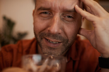 Portrait of mature drunk man looking at camera while drinking alcohol cocktail