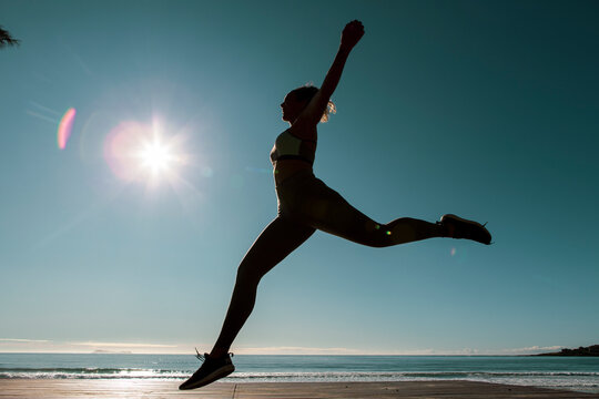 Young female dancer dances at sunset wearing sportswear . Silhouette backlight of the sun with body movements. Freedom and happiness concept. - Powered by Adobe