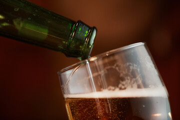 Close-up of cold beer in glass pouring from the bottle