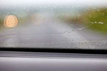 Fragment mokrej od deszczu szyby w samochodzie, widok z wnętrza auta. Rozmyte tło. - obrazy, fototapety, plakaty