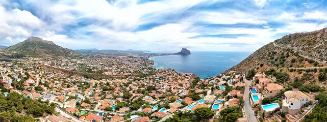 Aerial photography panoramic image Calpe or Calp townscape rooftops picturesque view to bright Mediterranean Sea waters and Parque natural Peñón de Ifach or Penyal de Ifac rock, Costa Blanca, Spain