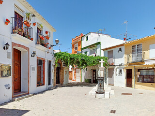 Pretty charming houses decorated with flowerpots ivy leaves in empty small square of Denia old...