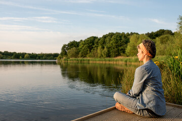 a woman sitting on a share of the lake and meditating