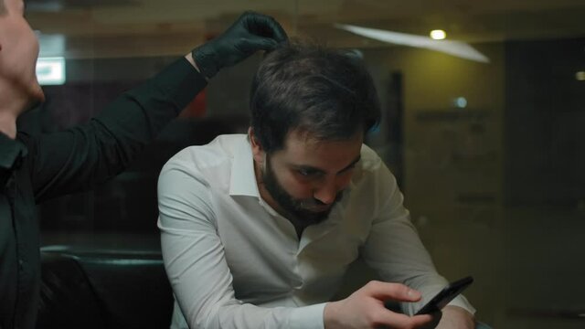 Bearded man explains to a barber his future haircut style. The master barber checks to see if he has hair and looks at his beard to get everything done. Inside of modern hipster barbershop.