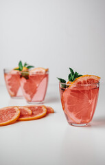 Pink drink, cocktail with grapefruit slice and fresh mint on a white background.