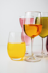 Glasses with multi-colored drinks on a white background.