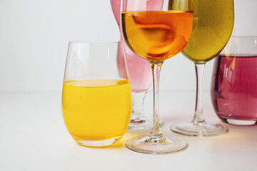 Glasses with multi-colored drinks on a white background.