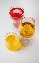 Glasses with multi-colored drinks on a white background.