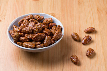 Amêndoas caramelizadas em um pote de cerâmica sobre mesa de madeira