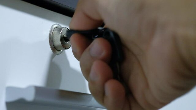 Using a key to open the lock of the drawer. Unlock door.