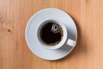Coffee in a white cup on a wood table on top view with space for copy text
