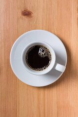 Coffee in a white cup on a wood table on top view 