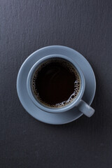 Coffee in a grey cup on a dark grey stone on top view