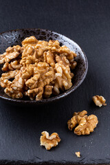 walnuts in a black bowl on a dark stone table