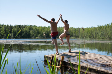 Man and woman jump to lake water together having fun