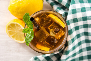 Iced tea drink with lemon in glass and ice on white wooden table. Top view